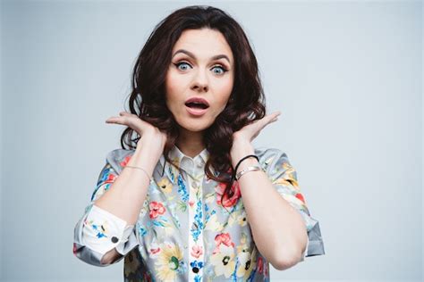 Morena de pelo rizado caucásico con ojos azules y maquillaje nude con emoción sorpresa en la