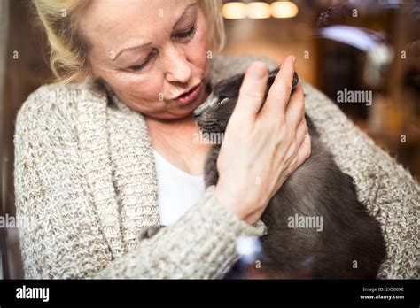 Beautiful Mature Woman At Home Holding Petting Her Cat Looking Through The Window Older