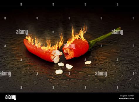 Red Hot Chilli Peppers And Chilli Seeds With Smoldering Fire Flames And Droplet Of Water