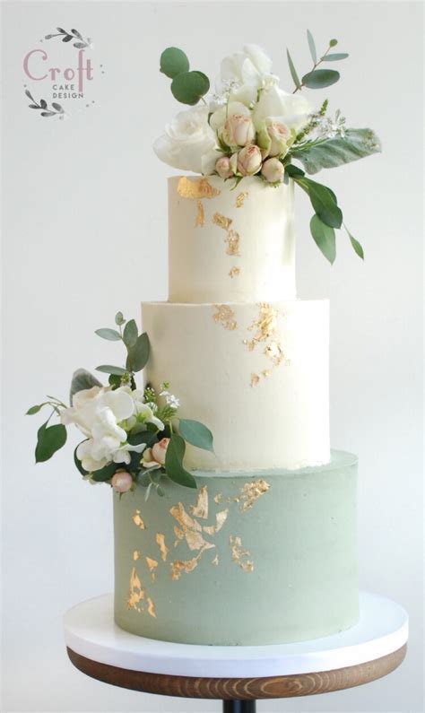 A Three Tiered Cake With White Flowers And Greenery On The Top Is