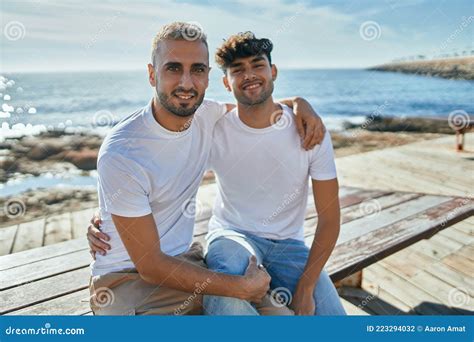 Jeune Couple Gay Souriant Heureux Assis Sur Le Banc De La Promenade De La Plage Photo Stock