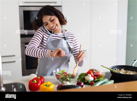 Cheerful Brunette Woman Checking Time While Cooking Having Phone Conversation Stock Photo Alamy