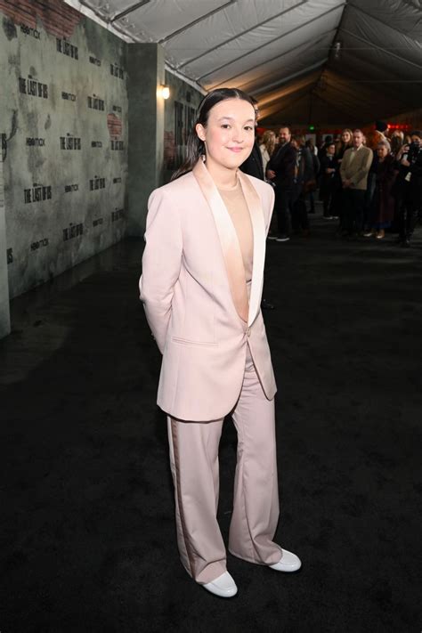 A Woman Standing In Front Of A Crowd Wearing A Pink Suit And White