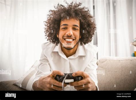 Arabe gay jouant à un jeu d ordinateur Le jeune homme tient le joystick de la Play Station