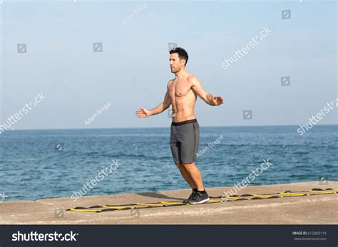 Athletic man with naked and muscular upper body making training on agility ladder超过 10 张免版税可许可的