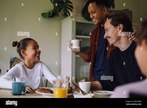 Happy Gay Couple With Daughter Having Breakfast While Sitting At Dining