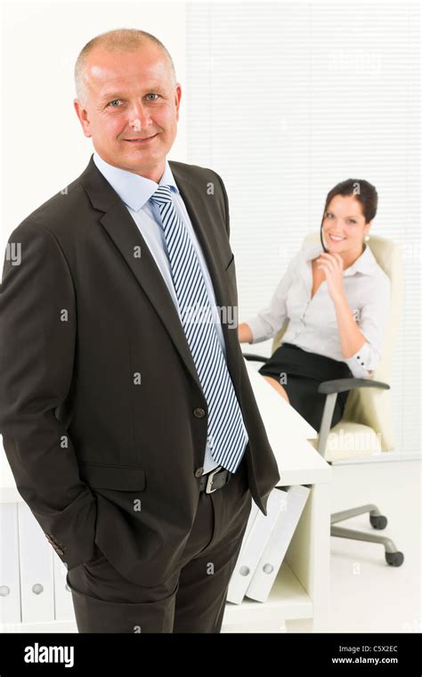 Professional Senior Mature Businessman Standing In Office With Attractive Secretary Stock Photo
