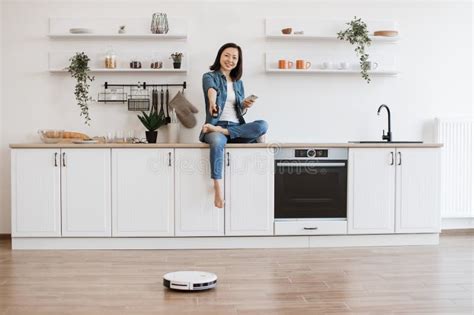 Housewife With Mobile Starting Cleaning With Robotic Vacuum Stock Image Image Of Brunette