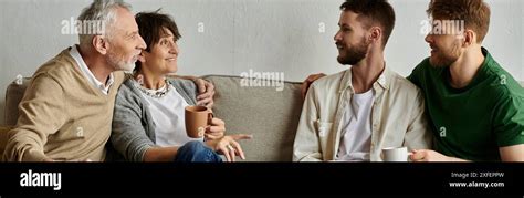 A Gay Couple Sits On A Couch With Parents Engaging In A Warm And Meaningful Conversation Stock
