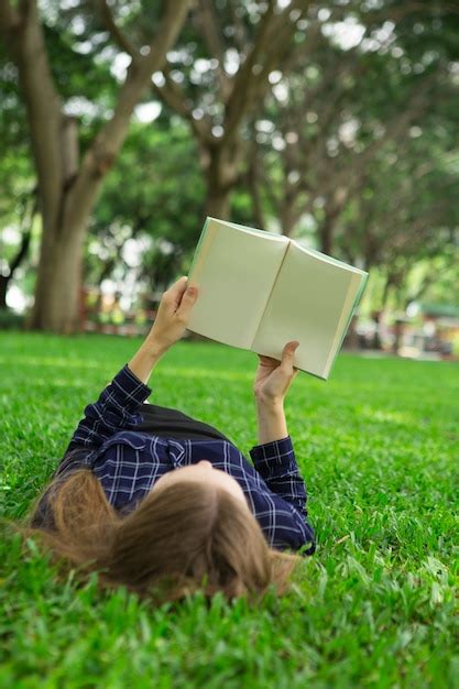 Free Photo | Young Girl Lying on Grass and Reading Book