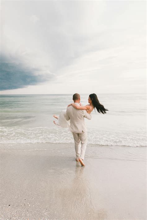Man Carrying Woman in Wedding Dress on the Sandy Beach · Free Stock Photo