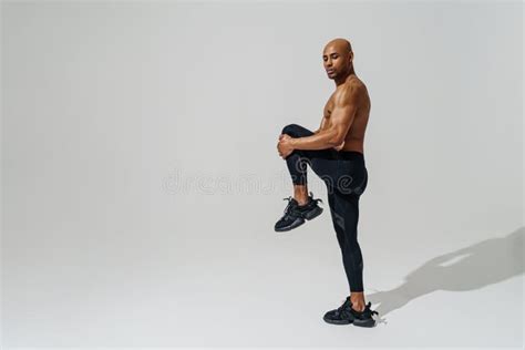 Athletic Man With Naked Torso Doing Leg Stretching Exercises Before Workout On Studio Background