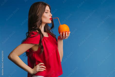 Beautiful Brunette Girl Drinking Natural Orange Juice Straight From The Orange Through A Straw