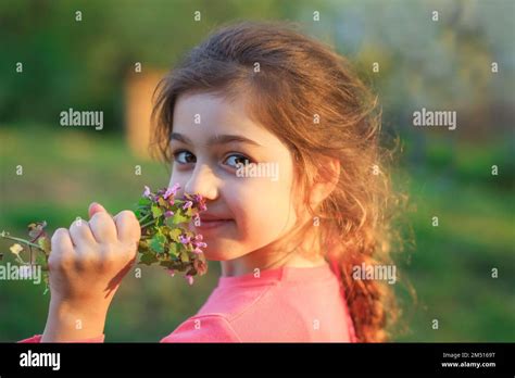 Little cute girl with pinc flowers. Child playing in summer garden. Kids gardening. Children ...