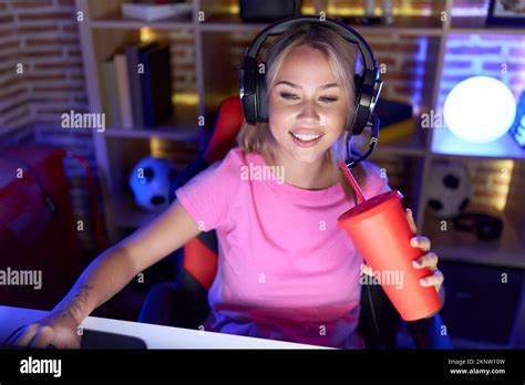 Jeune femme blonde streamer jouant au jeu vidéo boisson dans la salle de jeux Photo Stock Alamy