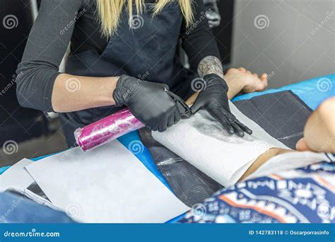 La Femme Blonde Dessine Un Tatouage Avec Sa Machine De Tatouage Photo Stock Image Du Concept