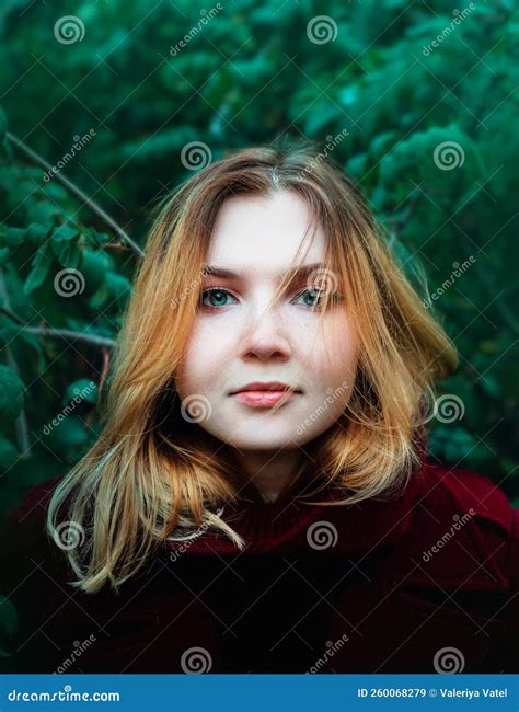 Portrait D Une Jeune Femme Blonde En Pelage Bordeaux Sur Fond De Feuillage Vert D Arbres Mode