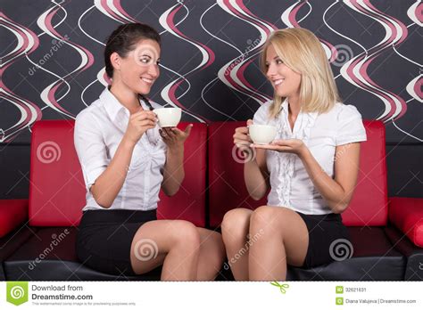 Mooie Donkerbruine En Blonde Zitting Op De Mede Bank En Drinken Stock Afbeelding Image Of