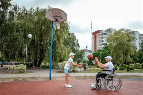 Premium Photo A Man In A Wheelchair Plays Basketball With His Son On