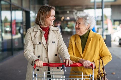 Mature Granddaughter Helping Grandmother Load Groceries In To The Car Senior Woman Shopping At