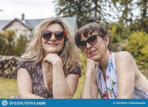 Ritratto Di Due Donne Mature E Amichevoli In Vacanza Posate Su Una Pila Di Legno Immagine Stock