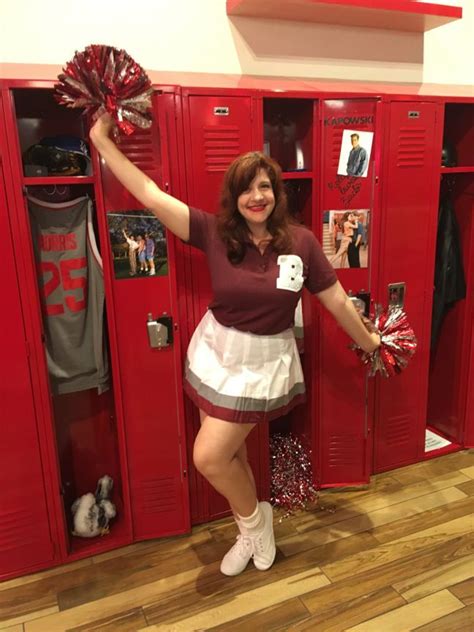 A Woman Standing In Front Of Lockers With Cheerleader Pom Poms