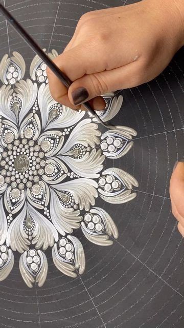 Two Hands Are Drawing An Intricate Design On A Piece Of Paper That Is