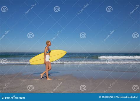 Frau Im Bikini Gehend Mit Surfbrett Auf Strand Im Sonnenschein Stockfoto Bild Von Strand