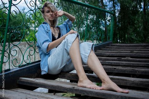Fotografia Do Stock A Blonde Girl Is Sitting On The Steps Of A Staircase With A Fence A Girl