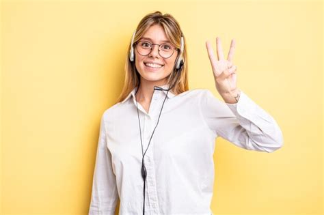 Jolie fille blonde souriante et semblant amicale montrant le numéro trois concept de casque