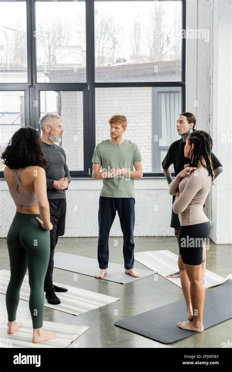 Interracial People Looking At Mature Coach While Standing On Mats In Yoga Class Stock Image