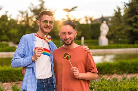 Premium Photo Portrait Of Gay Boyfriend And Girlfriend Eating A Lollipop In The Park On Sunset