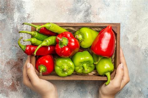 Free Photo Top View Red And Green Peppers Hot Peppers In Wooden Box In Woman Hands On Nude Surface