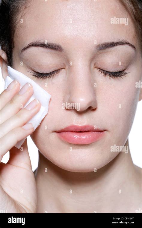 Female With Brunette Hair Off Her Face Rubbing Cheek With Cosmetic Sponge Unsmiling With Her