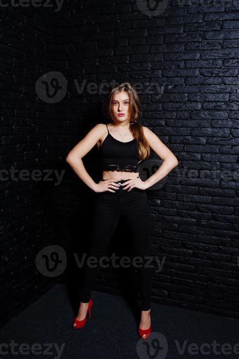 Handsome Brunette Girl Wear On Black And Red High Heels Posing At Studio Against Dark Brick