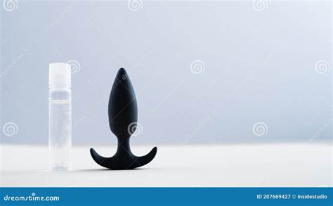 Ficha Anal Preta E Uma Garrafa De Lubrificantes Sobre Uma Mesa Sobre Fundo Branco Imagem De