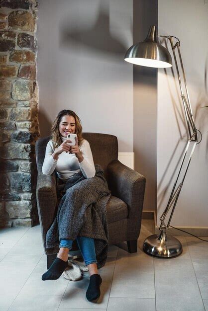 Junge blonde kaukasische Frau in der Wärme ihres Zuhauses auf dem Sofa telefoniert