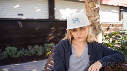 Placeit Blonde Woman Wearing A Snapback Hat Video Mockup While Sitting On A Bench Outdoors