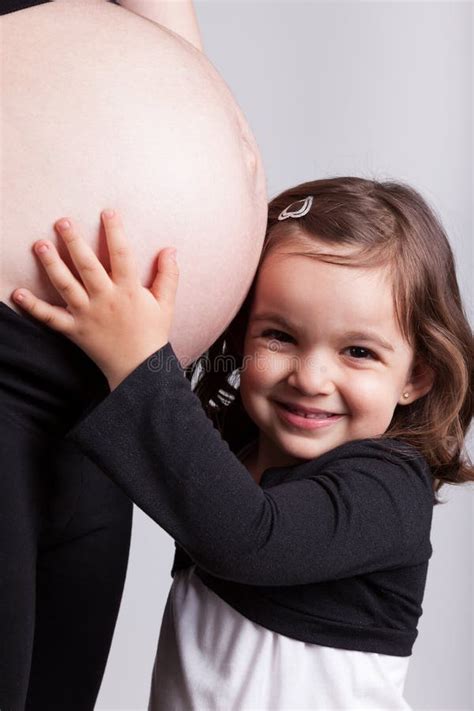 La Figlia Felice Abbraccia La Sua Pancia Incinta Della Madre Fotografia