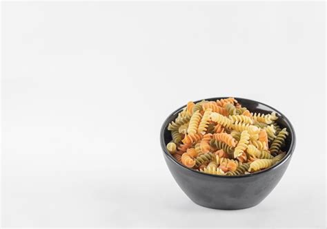 Free Photo Raw Colorful Fusilli Pasta In Dark Bowl