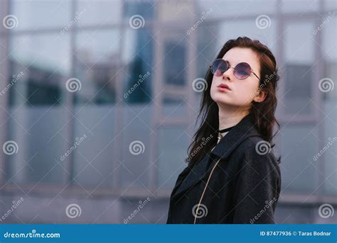 Stylish Portrait Of Beautiful Brunette Girl In Glasses Which Poses Against A Background Of Dark