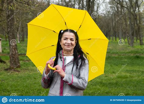 Happy Senior Woman In Yellow Rain Coat With Yellow Umbrella Encouraging