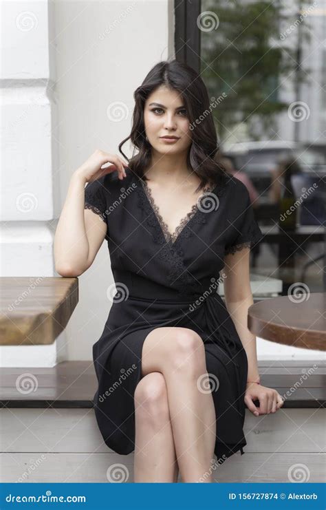 Das Schöne Elegante Brunette Mädchen Das Ein Schwarzes Kleid Mit Einem Sexy Tiefen Zerlegung