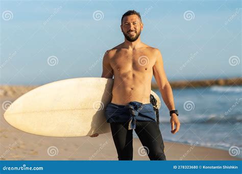 A Man Surfer With Naked Torso Standing On The Shore Holding A Surfing Board Stock Photo Image