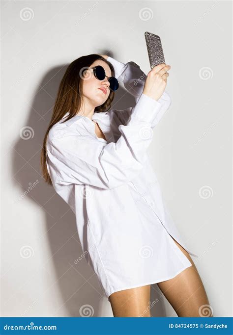Naked Girl In A Man S White Shirt And Sunglasses Holding Phone Doing Selfie Stock Image