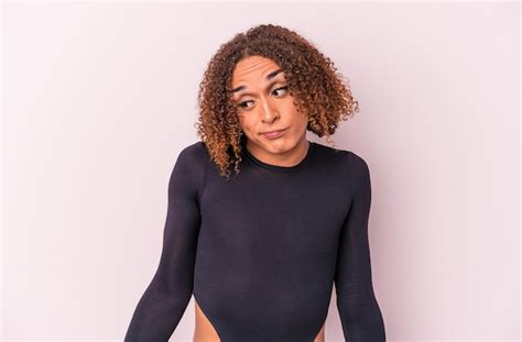Jovem Transexual Latina Isolada No Fundo Rosa Encolhe Os Ombros E Abre Os Olhos Confusos Foto