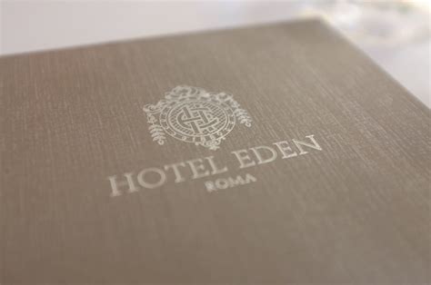 The Hotel Eden Logo Is Shown On Top Of A Brown Book With Silver Foil
