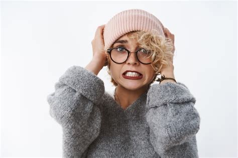 Portrait d une jolie femme blonde choquée mécontente et paniquée tirant un bonnet sur la tête