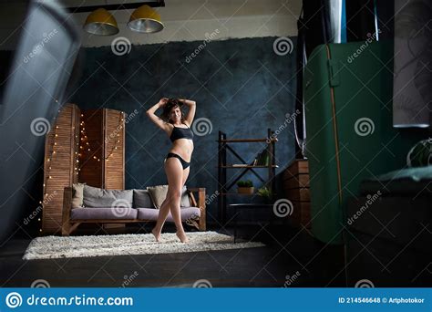 Beautiful Naked Busty Girl Sensually Stretches Against A Dark Background In An Apartment