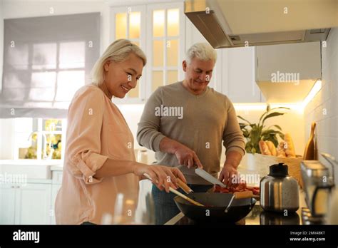 Mature Couple Cooking Food Together In Kitchen Stock Photo Alamy